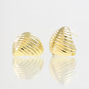 A pair of gold-toned, ribbed clamshell stud earrings on a reflective white surface against a light gray background.