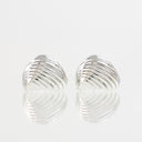 A pair of silver shell-shaped earrings with a textured, ridged surface, displayed on a reflective white surface against a light gray background.