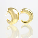 A pair of polished gold crescent-shaped hoop earrings on a reflective white surface.