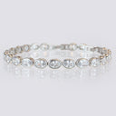 silver 4 mm oval CZ tennis bracelet displayed in a circle on a reflective surface.