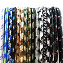A close-up row of braided cords or ropes shown in multiple colorways, including blue with green and yellow accents, black and tan camouflage, olive green, black and white, and black with small red accents.