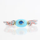 A silver-toned cuff bracelet featuring a central oval light blue bead with a blue faceted gemstone in the middle, accented by red and white braided cord and gold-toned knots on a reflective white background.