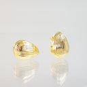 A pair of gold teardrop-shaped stud earrings with a ribbed, textured surface, displayed on a reflective white surface against a light gray background.
