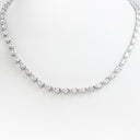 A silver tennis necklace featuring pear-cut clear gemstones, displayed on a white mannequin bust against a white background.