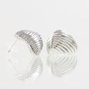 A pair of silver crescent-shaped stud earrings with a ribbed, textured surface, displayed on a reflective white surface against a light gray background.