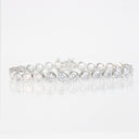 A silver tennis bracelet set with round brilliant-cut clear gemstones, displayed on a clean white reflective surface.