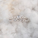 A pair of silver beaded eternity rings with clear round-cut gemstones, displayed on a bed of white salt crystals.