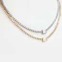 A close-up of a layered necklace set featuring three delicate strands: a yellow gold tennis chain with a square-cut clear gemstone pendant, a silver tennis chain with a matching square-cut clear gemstone pendant, and a gold and silver mixed-metal tennis chain. The necklaces are displayed on a clean white background.