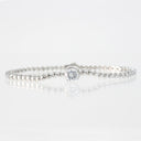 A silver beaded tennis bracelet with a single round-cut clear gemstone in a bezel setting, displayed on a reflective white surface.
