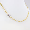 A gold paperclip chain necklace with a silver barbed wire charm, displayed on a white mannequin bust.