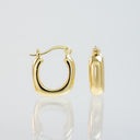 A pair of polished yellow gold hoop earrings, one shown from the front and the other from the side profile, displayed on a reflective light gray surface.