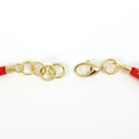 Gold-tone metal keychain strap components, including a lobster clasp and three interlocking rings, attached to red braided cord ends on a white background.