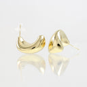 A pair of polished gold crescent-shaped stud earrings with clear silicone ear tips, displayed on a reflective white surface.