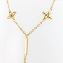 A gold Y-necklace featuring two small four-petal flower charms with tiny clear stones and a central vertical bar pendant, shown on a plain white background.