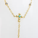 A gold Y-necklace featuring a central cross-shaped cluster with a small turquoise blue stone and clear round gemstones along the chain, displayed on a clean white background.