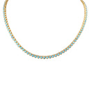 A gold tennis necklace featuring small round light blue turquoise-like stones set in a gold chain, shown against a plain white background.