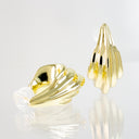 A pair of gold-toned sculptural stud earrings with a ribbed, organic shell-like form, shown on a reflective white surface against a light gray background.