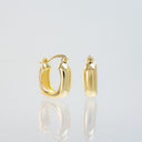A pair of polished yellow gold hoop earrings, one shown from the front and the other from the side, displayed on a reflective light gray surface.