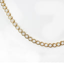A gold tennis necklace featuring round white opal-like inlays, photographed against a clean white background.