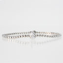 A silver beaded tennis bracelet with a central pear-cut clear gemstone, displayed on a reflective white surface against a light gray background.