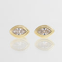 A pair of gold oval stud earrings with marquise-cut clear gemstones, displayed on a reflective light gray surface.