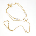 A gold chain necklace featuring a small gold cross, a gold star with a clear rhinestone, and two white pearl-like beads on a white background.