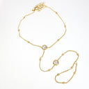 A delicate yellow gold chain necklace with two round bezel-set clear stones, displayed on a clean white background.