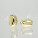 A pair of polished gold oval stud earrings with clear plastic display stands, shown on a reflective light gray surface.