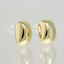 A pair of polished gold oval stud earrings with clear plastic backing, displayed on a reflective light gray surface.
