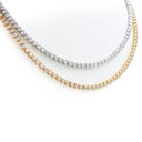 Two tennis-style necklaces on a white background, one in yellow gold and one in silver, both set with clear round stones.