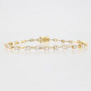 A yellow gold tennis bracelet featuring a row of marquise-cut clear gemstones, displayed on a clean white reflective surface.
