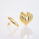 A pair of gold heart-shaped stud earrings with a ribbed, textured surface, one shown from the front and the other from the side displaying the post and butterfly back, on a reflective white surface.