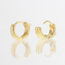 A pair of polished yellow gold huggie hoop earrings shown on a reflective white surface against a white background.