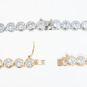 Two tennis-style jewelry pieces on a white background: a silver-tone bracelet across the top and a gold-tone clip-on bracelet across the bottom, both featuring clear round stones in bezel settings.