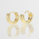 A pair of gold hoop earrings with a thick, polished three-bar design, displayed on a reflective white surface against a light gray background.