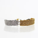 A double-strand mesh chain bracelet featuring one silver-toned chain, one gold-toned chain, and three white pearl-like beads at the center, displayed on a reflective white surface.