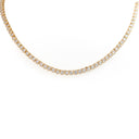 A gold tennis necklace with small clear stones set in a curved line on a plain white background.