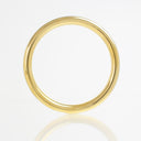 A polished yellow gold band ring with a smooth, rounded profile, displayed on a clean white reflective surface.