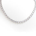 A tennis necklace featuring round brilliant-cut clear gemstones in a silver-toned metal setting, displayed against a clean white background.