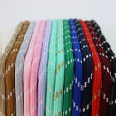 A close-up row of braided elastic cords or straps in multiple colors, including brown, gray, pink, lavender, mint, green, blue, navy, red, burgundy, and black, each with small white and gold woven accents.