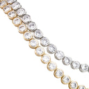 Two tennis-style bracelets with round bezel-set clear stones, shown on a white background. One bracelet is in yellow gold and the other is in silver.