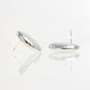 A pair of polished silver oval stud earrings with a ribbed texture, shown from both front and side angles on a reflective white surface.
