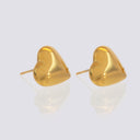 A pair of gold heart-shaped stud earrings with a polished finish, displayed on a light gray reflective surface.