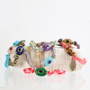 Four colorful woven cord bracelets with evil eye beads, displayed on a rustic wooden block against a white background.