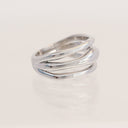 A polished silver ring with three overlapping, wavy bands, displayed on a clean white reflective surface.