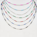 Six beaded strands of necklaces arranged in a fan shape on a plain white background. The necklaces feature small metallic beads in various colors including pink, light blue, green, red, black, and silver.