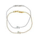 Three delicate snake-themed bracelets in mixed metals, featuring clear pavé-set stones and small green emerald accents, arranged on a plain white background.