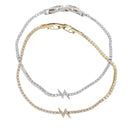 Two tennis-style bracelets with clear cubic zirconia stones, one in silver-tone metal and one in yellow gold-tone metal, each featuring a matching lightning bolt charm. The bracelets are arranged on a plain white background.