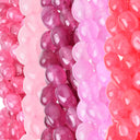 Close-up of multiple strands of glossy, translucent oval beads in shades of pink, magenta, and coral red.