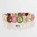 A multicolor stretch bracelet featuring rectangular cabochon gemstones in pink, green, yellow, orange, and beige, displayed on a reflective white surface with the text '#01' below.